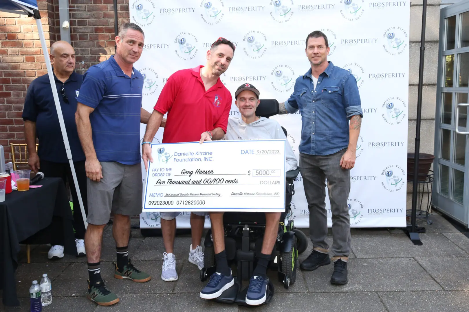 Group presenting large check to man in wheelchair.