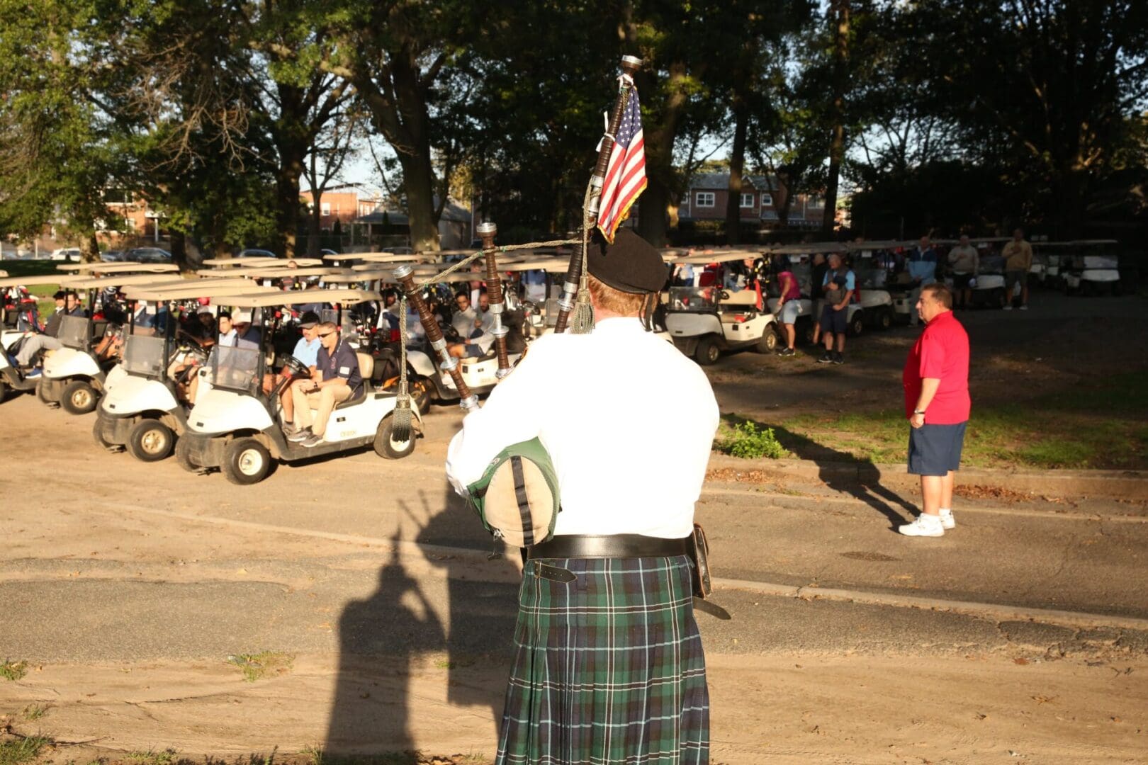 Man in kilt plays bagpipes with American flag.